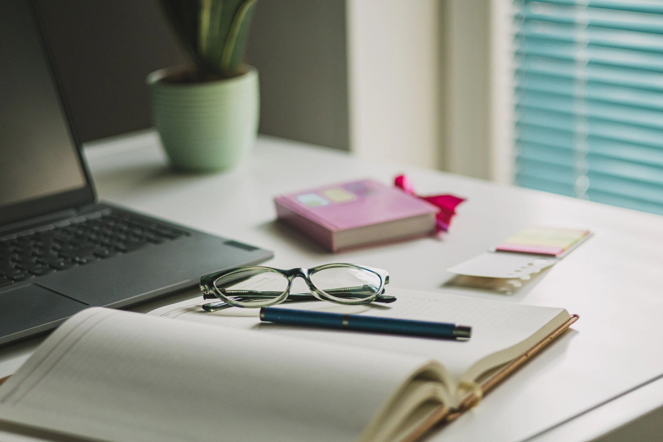 Minimal desk with laptop, coffee, and reading glasses